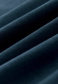 Gros plan d'un tissu bleu foncé montrant des plis doux et une texture fine en maille.