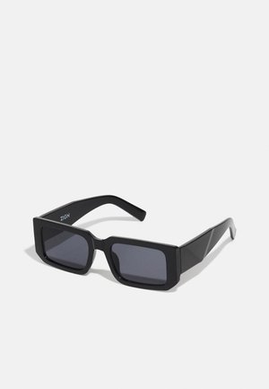 Black rectangular sunglasses with thick frames and dark lenses. Designed with angular edges and a subtle logo on the temple.