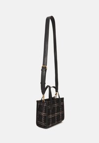Czarna torebka wzorzysta, wykonana z teksturowanej tkaniny, z górnymi uchwytami i odpinanym, regulowanym paskiem. Złote akcenty z metalu.