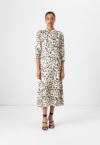 Maxikleid aus cremefarbigem Stoff mit schwarzen botanischen Mustern. Es hat einen Kragen, eine durchgehende Knopfleiste und halblange Ärmel. Der Saum ist fließend.