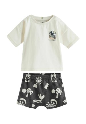 Cremefarbenes Baby-Kurzarmshirt mit "Take it easy" Strand-Grafik und schwarzen Shorts mit weißem Tropenmuster.
