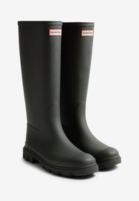 Bottes de pluie en caoutchouc noir avec une texture lisse, hauteur mi-mollet et semelle robuste ; étiquette de marque "HUNTER" en rouge et blanc sur la tige.