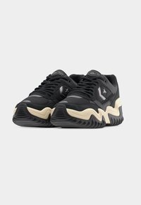 Μαύρα δερμάτινα και υφασμάτινα αθλητικά παπούτσια με χοντρή σόλα σε κρεμ και μαύρο, με λογότυπο αστεριού και υφασμάτινες λεπτομέρειες στο επάνω μέρος.