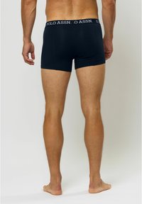 Kék pamut boxer alsónadrág elasztikus derékpánttal, rajta az "U.S. Polo Assn." logó, hátulról nézve, szoros illeszkedés és sima textúra.
