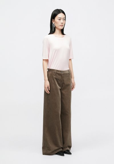 Light pink short-sleeve top paired with wide-leg brown corduroy pants. Black pointed-toe shoes and long bead earrings complete the look.