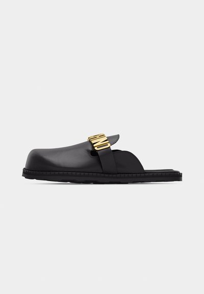 Μαύρο σανδάλι τύπου slip-on με κλειστή στρογγυλή μύτη, επίπεδη σόλα και ρυθμιζόμενο λουράκι με διακοσμητικά γράμματα σε χρυσό τόνο.