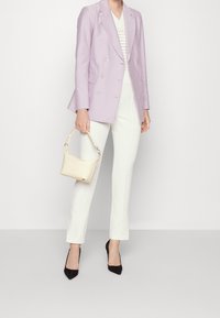 Błękitny żakiet dwurzędowy, biały top o fakturze, kremowa torebka z uchwytem, białe dopasowane spodnie, czarne szpilki. 