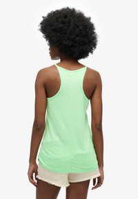 Lysegrøn ærmeløs tanktop med racerback-design, lavet af blødt stof, med en afslappet pasform og buet kant.