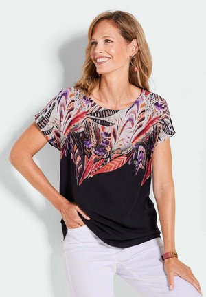 Blouse à manches courtes présentant un motif de feuilles colorées en violet, rouge et blanc sur fond noir ; le tissu semble lisse et léger.