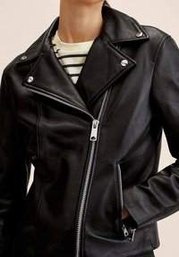 Veste de moto en cuir noir avec col cranté, quincaillerie argentée, fermetures éclair diagonales, et une coupe ajustée. Chemise rayée visible en dessous.