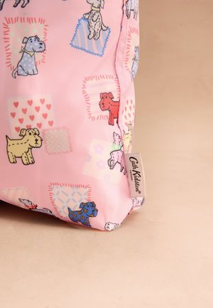 Rožnata tkanina z barvitimi risanimi psi in vzorci patchwork, na strani je bela etiketa Cath Kidston London.