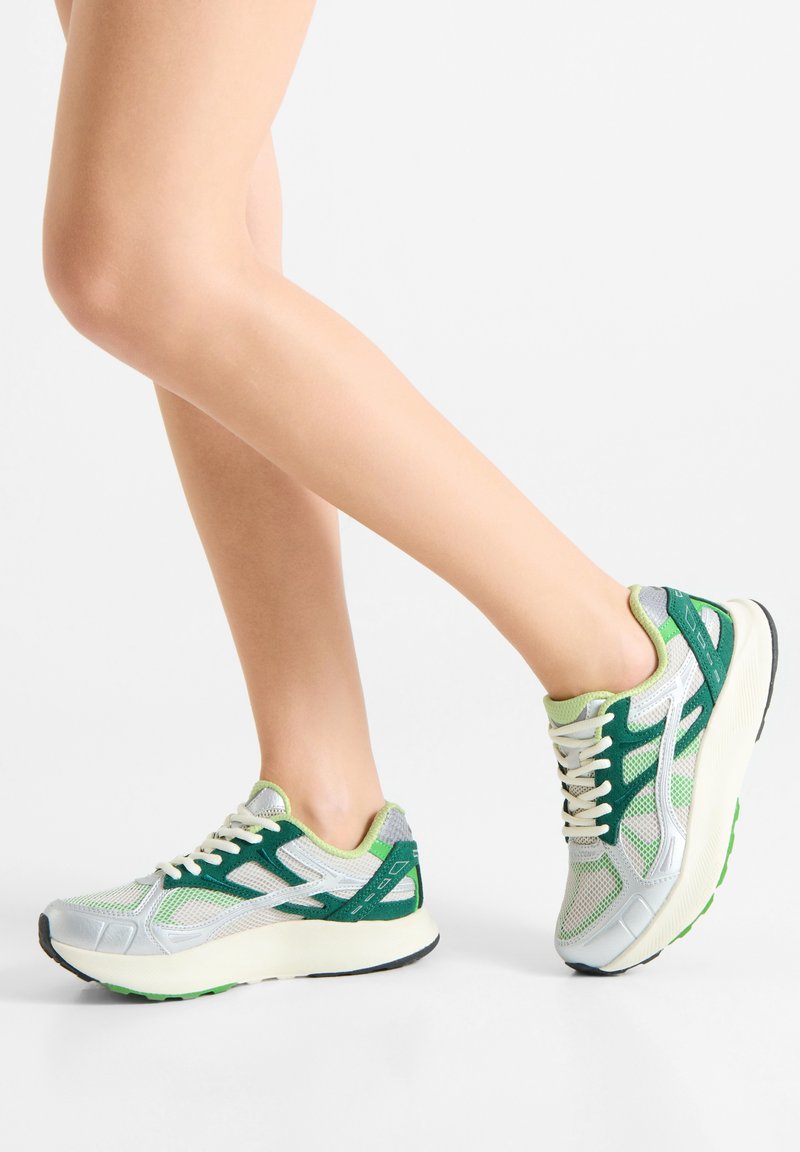 Men's running shoes featuring a mesh upper in gray with green accents, a rounded toe, and a cushioned sole for support.