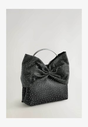 Sac à main noir avec un haut en forme de nœud, fabriqué en tissu texturé et orné de petites clous argentés. Présente une anse en métal circulaire.