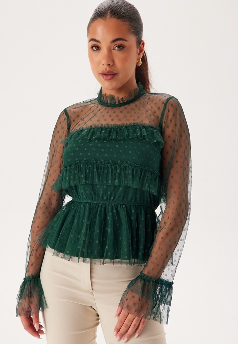 Groene blouse met gelaagde ruffles, transparante lange mouwen en een stippenpatroon. Heeft een hoge halslijn en een gestructureerde stof.