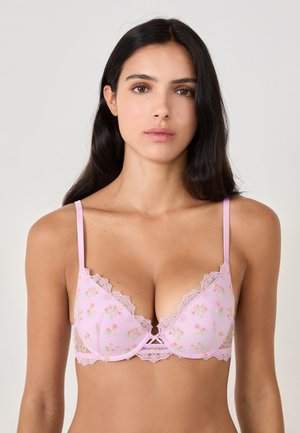 Light pink bra with floral embroidery, lace detailing along the edges, adjustable straps, and a small bow at the center.