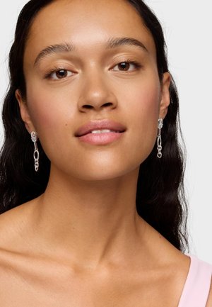 Pendientes de plata con un diseño de cadena interconectada, con una parte superior circular y una caída de cadena alargada, que exhiben un acabado metálico suave.