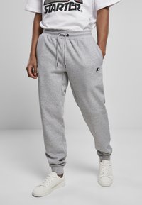 Grijze joggingbroek gemaakt van zacht materiaal, met een elastische tailleband met koord, zijzakken en een klein logo op de bovenbeen.