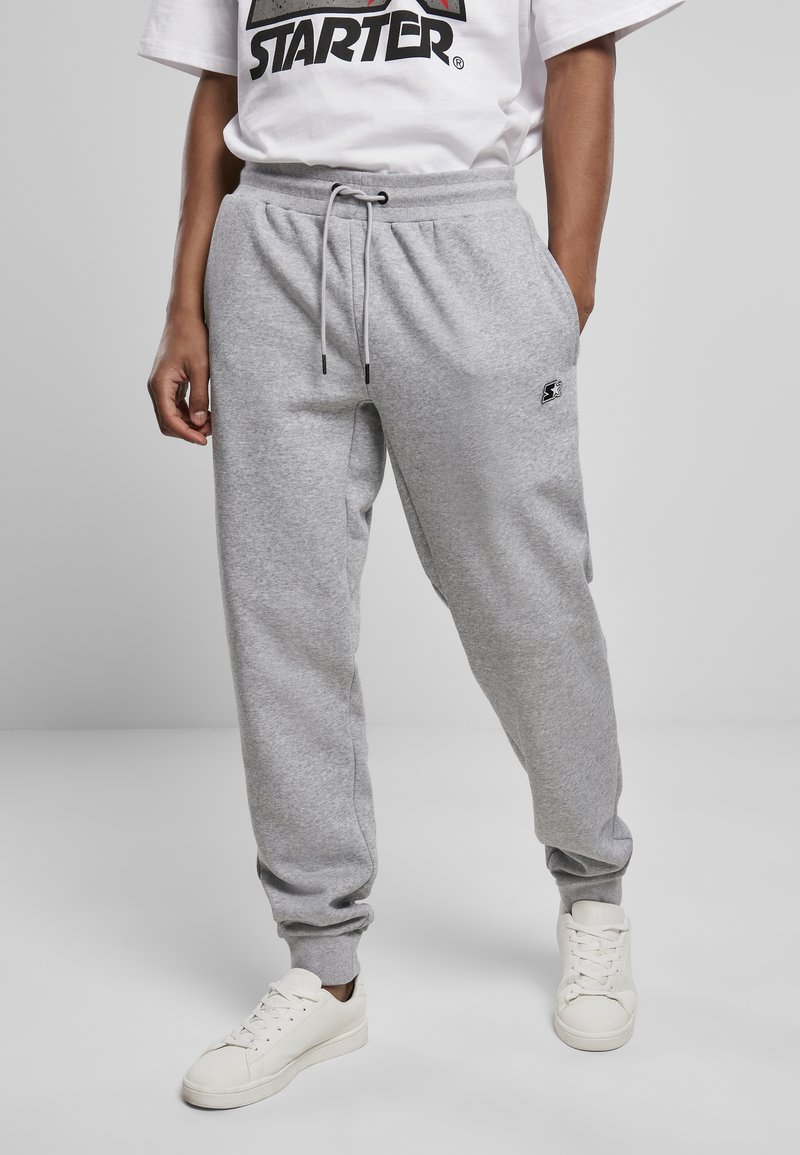 Grijze joggingbroek gemaakt van zacht materiaal, met een elastische tailleband met koord, zijzakken en een klein logo op de bovenbeen.