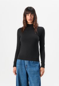 Maglione nero a manica lunga con collo alto, realizzato in un tessuto liscio. Caratterizzato da un design aderente e dettagli a coste visibili sull'orlo.
