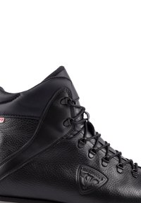 Stivale in pelle nera con finitura testurizzata, design alto, lacci standard, dettaglio logo sul lato e accenti lisci alla caviglia.