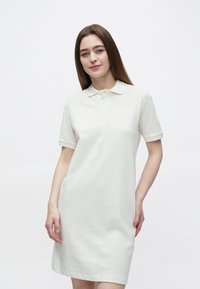 Polo obleka iz svetlo bež tkanine, z ovratnikom, gumbe spredaj in kratkimi zavihanimi rokavi, z rahlo prilegajočim krojem.