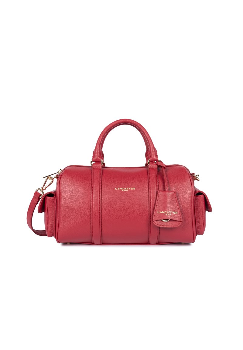 Borsa a mano in pelle rossa con accessori in oro, forma rotonda, tracolla laterale e un'etichetta piccola. Presenta una superficie testurizzata e dettagli cuciti.