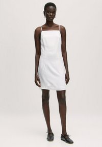 Weißes Spaghettiträgerkleid mit quadratischem Ausschnitt, aus leichtem Stoff gefertigt, mit geradem Schnitt und minimalistischem Design.
