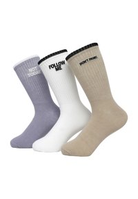 Trzy pary skarpetek załogowych: lawendowe z napisem "NIE DZIŚ", białe z napisem "ŚLEDŹ MNIE" oraz beżowe z napisem "NIE PANIKUJ", wszystkie z prążkowanymi mankietami.