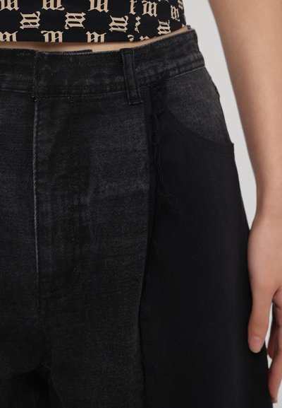 Sorte denimbukser med en blanding af struktureret og glat stof, synlige syninger og en sidelomme, skåret i taljen.