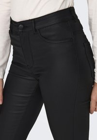 Czarne skinny jeans wykonane z gładkiego, elastycznego materiału. Posiadają wysoki stan, przednie kieszenie i czyste szwy, które nadają elegancki wygląd.