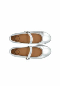 Bailarinas metálicas plateadas con punta redondeada, correa ajustable y textura suave. El interior presenta una plantilla color marrón y el logo de la marca.