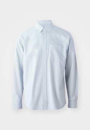 Camisa de manga larga azul claro fabricada en algodón. Presenta un collar con botones, botones frontales y un bolsillo en el pecho del lado izquierdo.