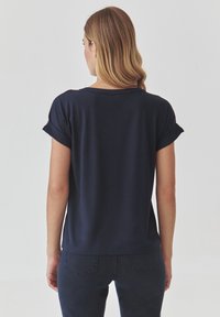 Marineblaues T-Shirt mit kurzen Ärmeln und lockerer Passform, mit umgeschlagenen Ärmeln und Rundhalsausschnitt. Weicher, glatter Stoff mit schlichtem Design.