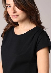Zwart kortmouwtop met een ronde halslijn, gemaakt van zachte stof. Heeft een ontspannen pasvorm en een subtiele textuur, geschikt voor casual draag.