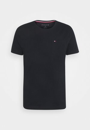 T-shirt noir à manches courtes et col rond avec une petite poche sur la poitrine gauche présentant un petit logo rouge, blanc et bleu.