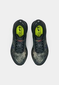 Ein Paar dunkelgraue Nike-Laufschuhe mit gemusterten Obermaterialien und neongrünen Einlegesohlen, von oben auf einem weißen Hintergrund betrachtet.