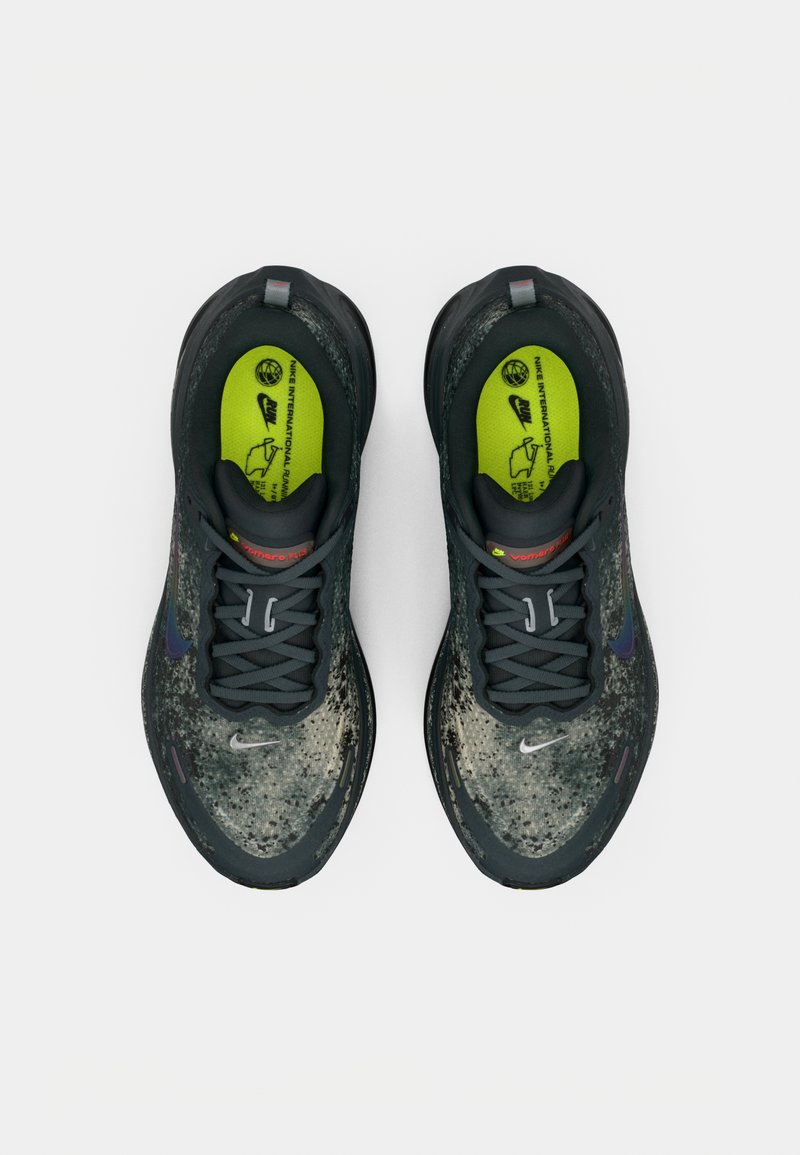 Pair of dark gray Nike running shoes with patterned uppers and neon green insoles, viewed from above on a white background.