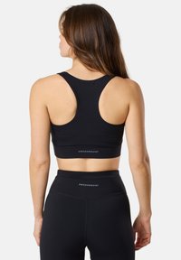 Svart sport-BH och högmidjade leggings i mjukt tyg. BH:n har racerback-design; båda har "SWEDEMOUNT"-logotypen.