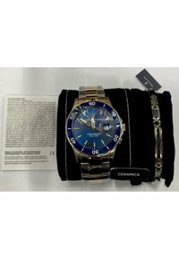 Blaue und silberne Armbanduhr mit einem Band aus Edelstahl und Goldelementen. Sie verfügt über ein strukturiertes blauen Ziffernblatt, ein Datumsdisplay und ein wasserdichtes Gehäuse.