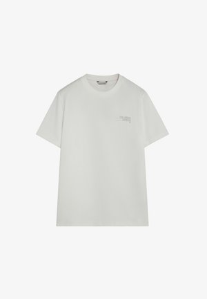 Camiseta blanca de manga corta con cuello redondo y pequeño texto gris "THE URBAN GARDEN" en el pecho izquierdo.