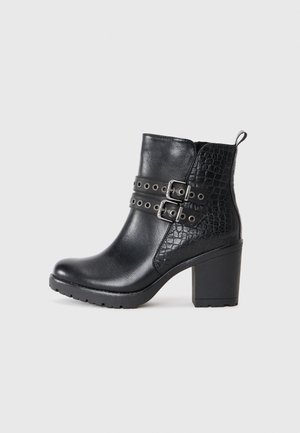 Bottines noires en cuir lisse et embossé, avec des sangles à double boucle, un talon épais et un panneau latéral texturé.