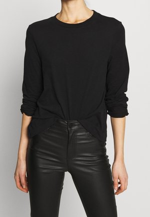 Black long-sleeve t-shirt in soft cotton, featuring a crew neckline and relaxed fit, paired with fitted black faux leather pants.