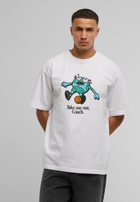 T-shirt en coton blanc à manches courtes avec un dessin coloré d'un personnage sur le devant et le texte "Emmène-moi, entraîneur." en dessous.