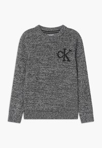 Grå stickad tröja med ett texturerat mönster, rund hals och långa ärmar. Har en svart logotyp "ck" på vänstra bröstet.