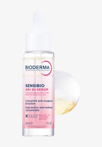 Klares Glas-Tropfflasche mit weißem Deckel, enthält ein hellgelbes Serum. Etikett in Pink und Blau, weist auf anti-Rötungs-Eigenschaften hin.