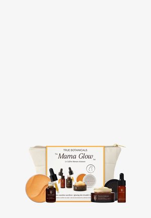 Il set include una crema e oli in bottiglie di vetro ambra, un balsamo giallo e una pochette con dettagli dorati. Presenta colori neutri e varie texture.