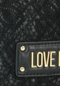 Borsa nera con dettagli in pizzo testurizzato, borchie in metallo color oro e una targa dorata "LOVE ME". Pannello in pelle liscia.