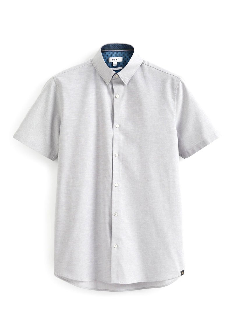 Camisa de manga corta en tejido gris claro, con un frente abotonado, un cuello interior azul estampado y un dobladillo ligeramente curvado.