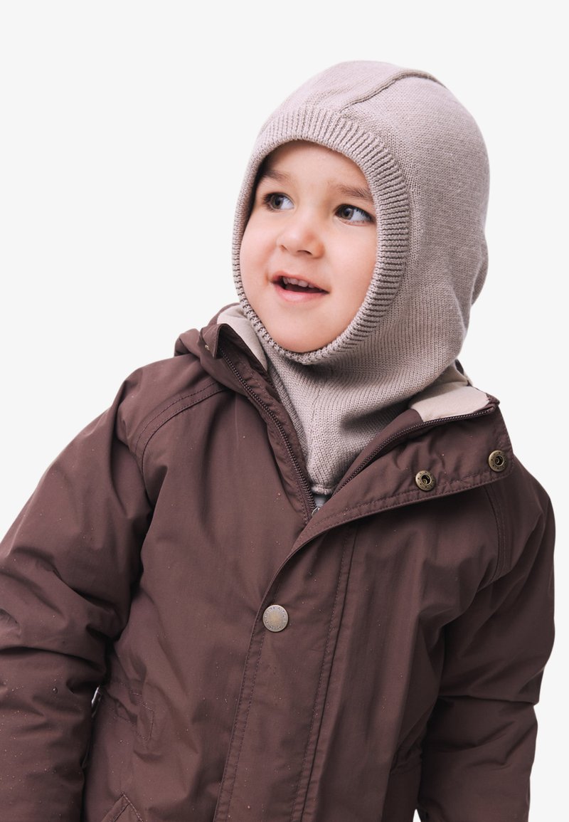 Doudoune marron avec un passe-montagne en tricot beige. La veste dispose d'une fermeture éclair et de boutons-pression, avec une texture douce et une coupe ajustée.