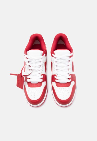 Ζευγάρι λευκά και κόκκινα αθλητικά παπούτσια χαμηλού ύψους με λευκά κορδόνια και κόκκινη ετικέτα προσαρτημένη στο αριστερό παπούτσι, εμφανιζόμενα από επάνω με φόντο λευκό.